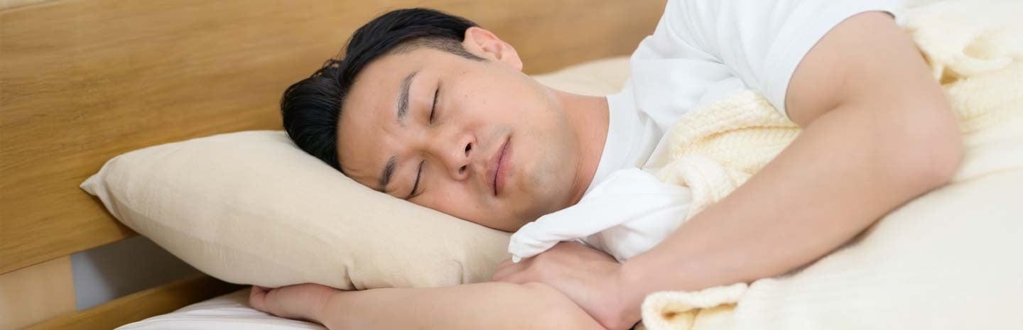 Man sleeping in bed - managing obstructive sleep apnoea