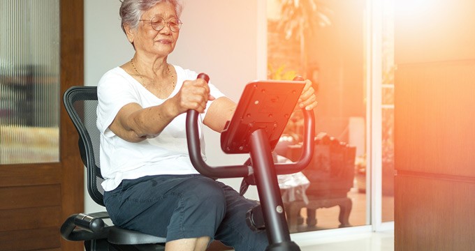 Elderly lady uses an exercise bike