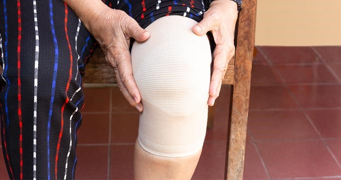 A person uses a knee compression bandage