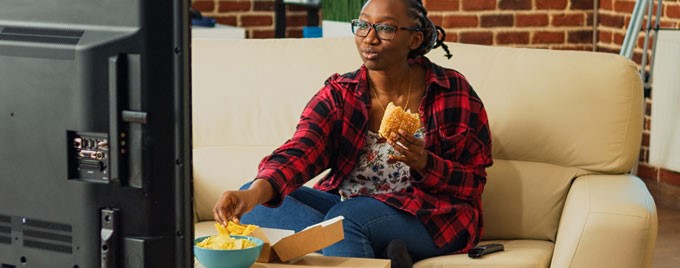 A woman eating as she watches TV