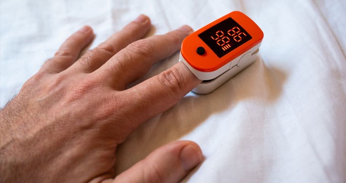 A person uses a pulse oximeter to measure their oxygen levels